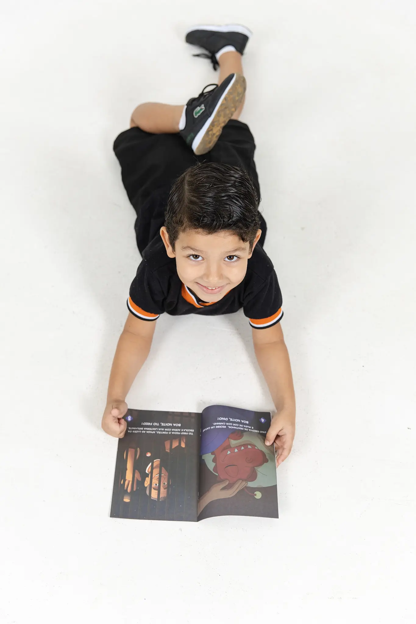 Menino deitado lendo um livro da Turma do Nick