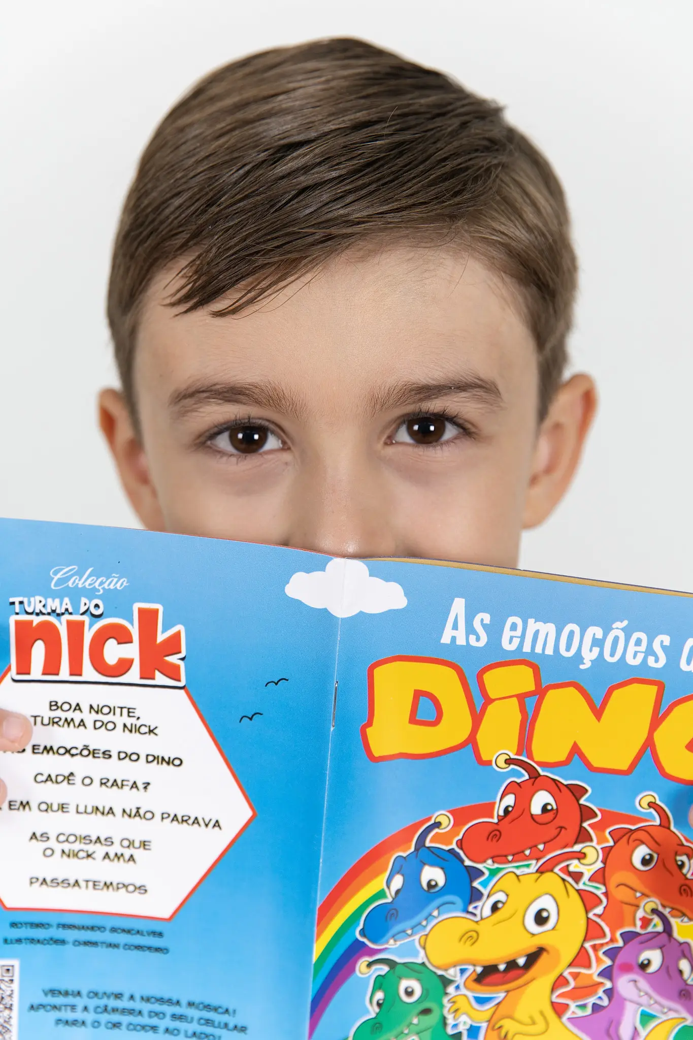Menino espiando por cima do livro As emoções do Dino