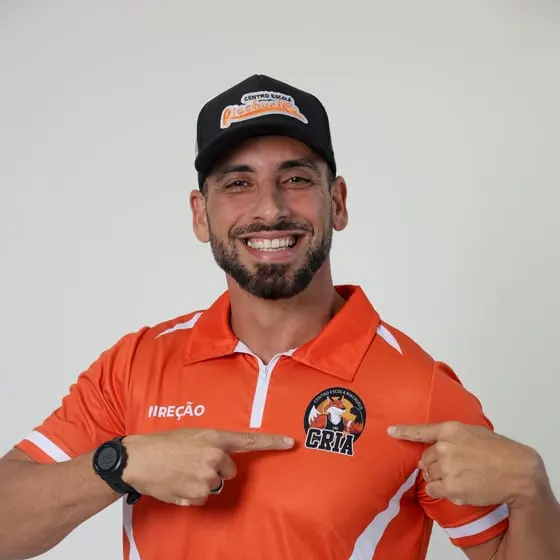 Integrante da direção do Riachuelo sorrindo e apontando para o escudo dos Crias na camisa