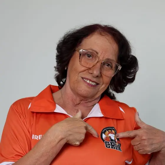 Integrante da direção do Riachuelo sorrindo e apontando para o escudo dos Crias na camisa