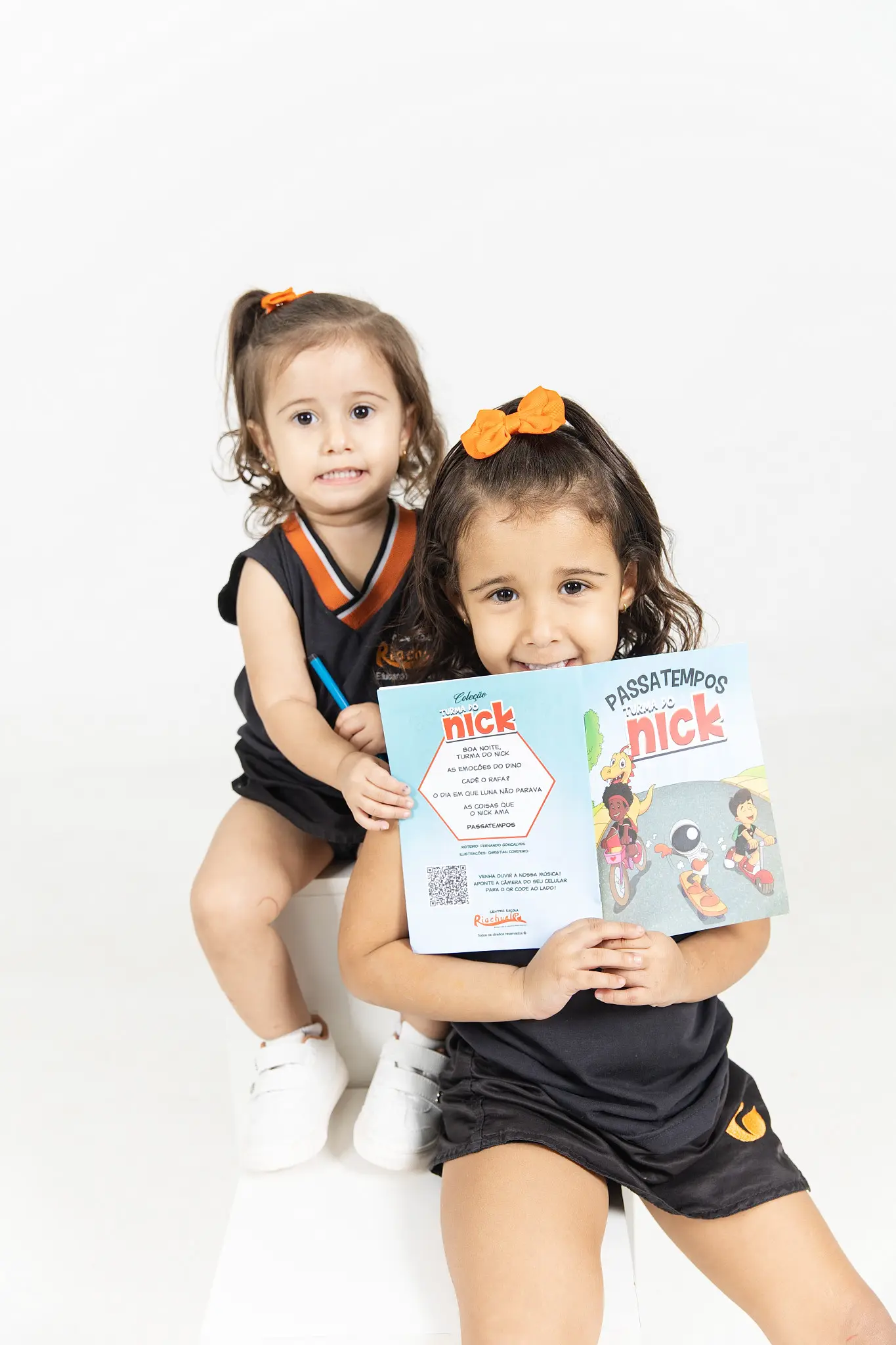 Duas amigas abraçadas segurando livros da Turma do Nick