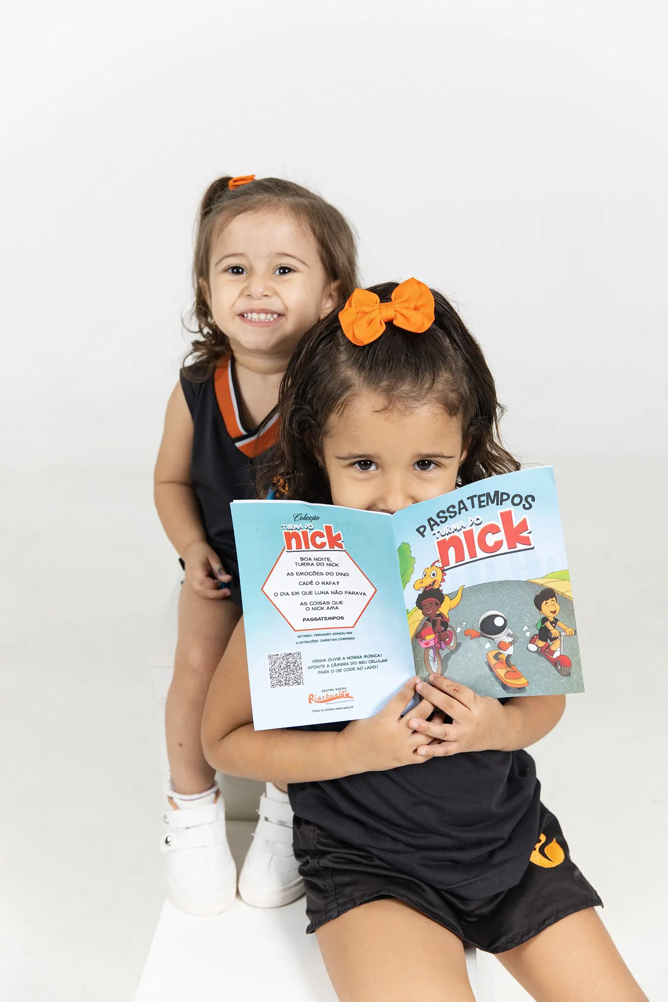 Duas meninas mostrando livros da Turma do Nick