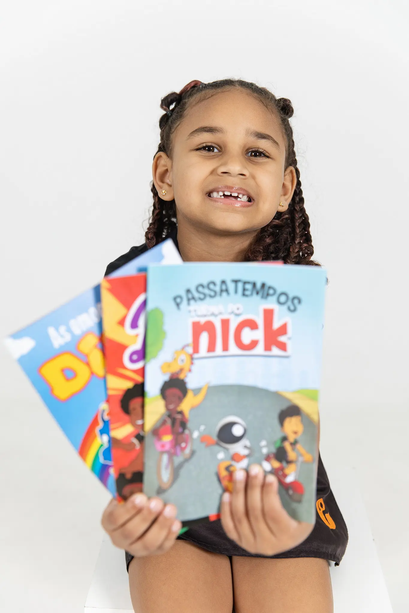 Menina sorrindo mostrando os livros de passatempos da Turma do Nick