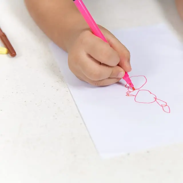 Mão de criança desenhando com caneta rosa