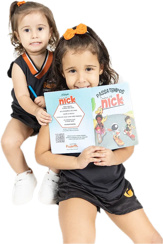 Duas alunas pequenas abraçadas, sorrindo com um livro da Turma do Nick